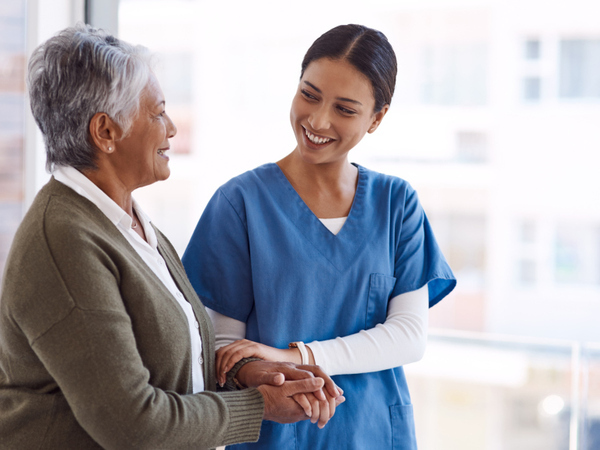 A carer supporting a woman to walk
